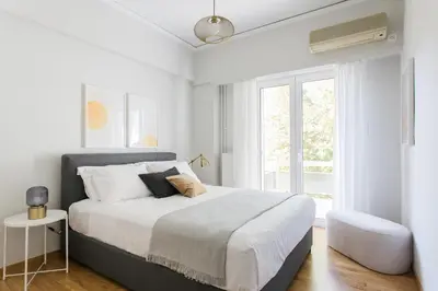 a white bedroom with a large bed and a window at Absolute 2BR Apartment near EMST Museum by UPSTREET in Athens