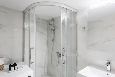 a white bathroom with a shower and a sink at Absolute 2BR Apartment near EMST Museum by UPSTREET in Athens