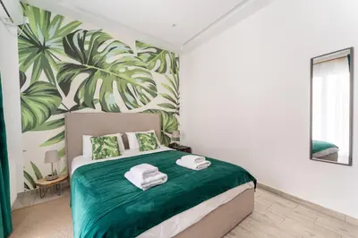 a bedroom with a green bed with a tropical wallpaper at Acropolis Royal Suite in Athens