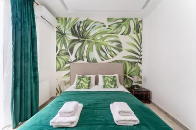 a bedroom with a green bed with a tropical wallpaper at Acropolis Royal Suite in Athens