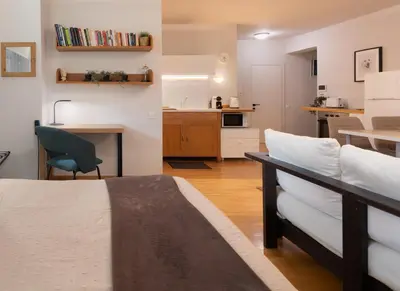 a bedroom with a bed and a kitchen with a table at Bright, Cosy Studio close to Glyfada Beach & Center in Athens