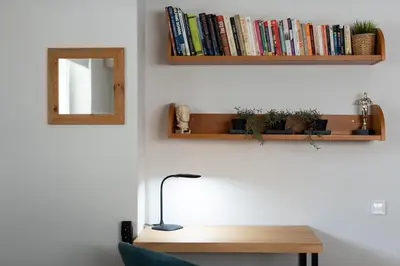 a desk with a lamp and books on a wall at Bright, Cosy Studio close to Glyfada Beach & Center in Athens