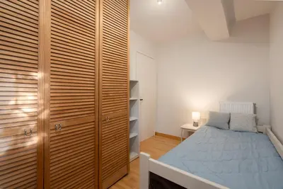 a bedroom with a bed and a wooden closet at Bright, Cosy Studio close to Glyfada Beach & Center in Athens