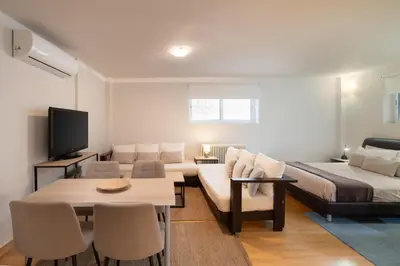 a living room with a couch and a bed and a table at Bright, Cosy Studio close to Glyfada Beach & Center in Athens