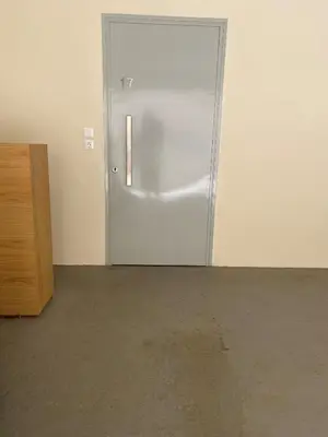 a silver door in a room with a concrete floor at Bright, Cosy Studio close to Glyfada Beach & Center in Athens