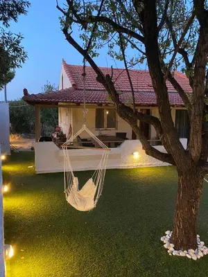 a hammock hanging from a tree in front of a house at La casa de PortoRafti in Porto Rafti