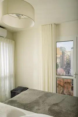 a white bedroom with a bed and a window at ERMOU STREET APARTMENTs in Athens