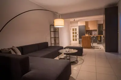 a living room with couches and a table and a kitchen at It is a pleasant, modern, functional house! in Piraeus