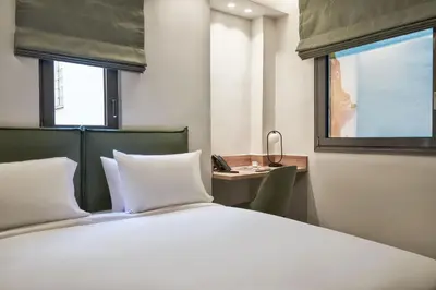 a bedroom with a bed and a desk and a window at NLH KERAMEIKOS - Neighborhood Lifestyle Hotels in Athens