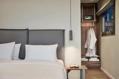 a bedroom with a white bed and a closet at NLH KERAMEIKOS - Neighborhood Lifestyle Hotels in Athens