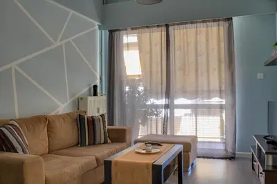 a living room with a couch and a table and a window at Modern Cozy Apartment in Downtown Athens in Athens