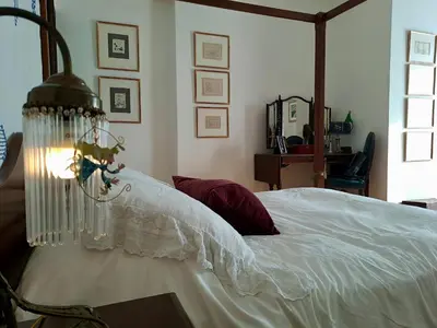 a bedroom with a bed with white sheets and a chandelier at The Magnolia - Sophisticated residence in Athens