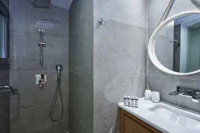 a bathroom with a shower and a sink and a mirror at Ilisia Park Contemporary 2BD Condo in Athens