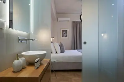 a bathroom with a sink and a bed and a mirror at Ilisia Park Contemporary 2BD Condo in Athens
