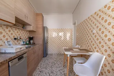 a small kitchen with a table and white chairs at Marina Zeas Livemodern in Piraeus