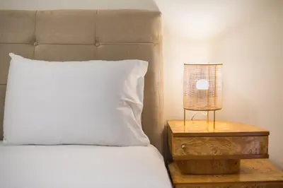 a bed with a white pillow and a lamp on a night stand at Boutique Suite by CloudKeys in Athens