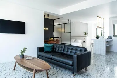 a living room with a black leather couch and a table at Here Comes The Sun in Athens
