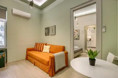 a living room with an orange couch and a table at Plaka Filotheis House A in Athens