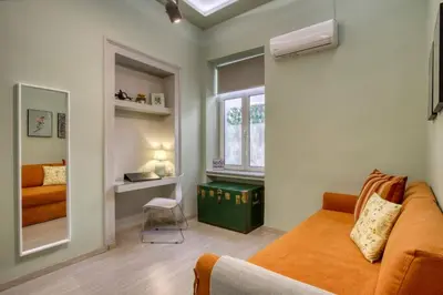 a bedroom with an orange couch and a window at Plaka Filotheis House A in Athens