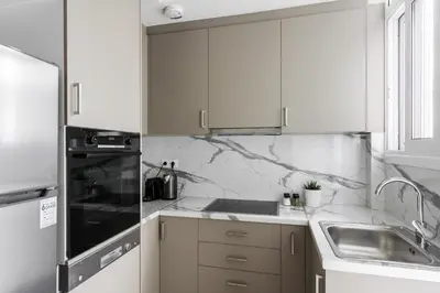 a white kitchen with white cabinets and a sink at Pristine 1BR Apartment in Ampelokipoi Area by UPSTREET in Athens