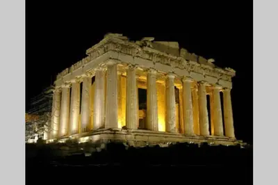 a lit up building with columns at night at Georgia's Cozy Apartment in Koukaki in Athens