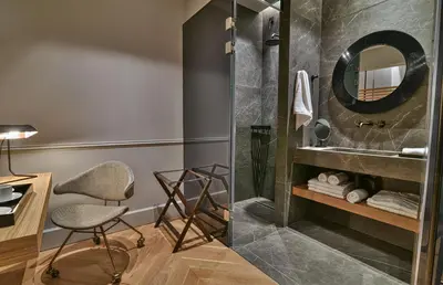 a bathroom with a shower and a desk and a chair at Athens Dom Hotel in Athens