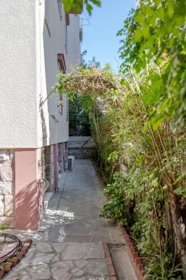 an alleyway between two buildings with plants at Paleo Faliro Gardenbay in Athens