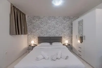 a bedroom with a large white bed with two lamps at Paleo Faliro Gardenbay in Athens