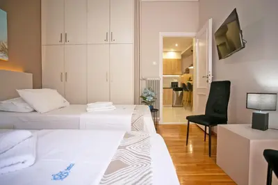 a hotel room with two beds and a chair at Semeli by Heloni Apartments in Athens