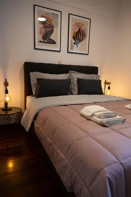 a large bed in a bedroom with two pictures on the wall at Spacious apartment close to the sea and the city center in Athens