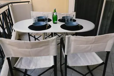 a white table with four chairs and a bottle of wine at Spacious apartment close to the sea and the city center in Athens