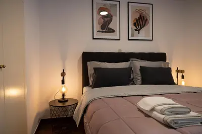 a bedroom with a bed with two pictures on the wall at Spacious apartment close to the sea and the city center in Athens