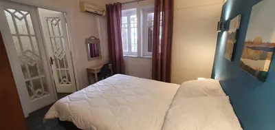 a bedroom with a white bed and two windows at Beauty of Central Athens 60sqm in Athens