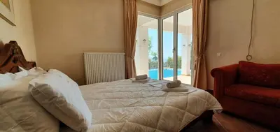 a bedroom with a bed and a couch and a window at Athenian Luxury Villa in Glyfada in Athens