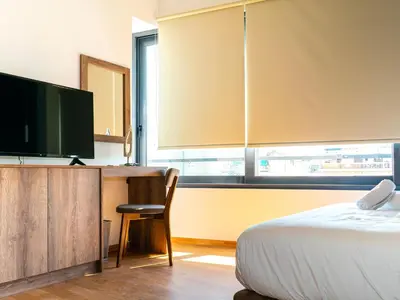 a bedroom with a bed and a desk with a television at Iasonos Suites Athens in Athens