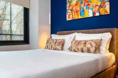 a bed with two pillows and a painting on the wall at Iasonos Suites Athens in Athens