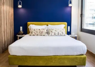 a bedroom with a large bed with a yellow headboard at Iasonos Suites Athens in Athens