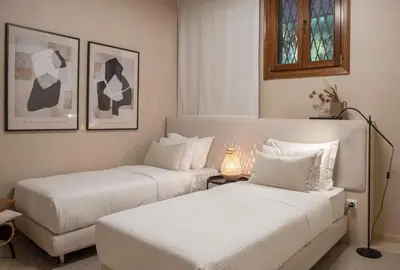two beds in a hotel room with white sheets at Villa Terra Mare in Vari
