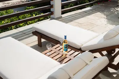 a table with two white chairs and a bottle of alcohol at Villa Beis in Porto Rafti