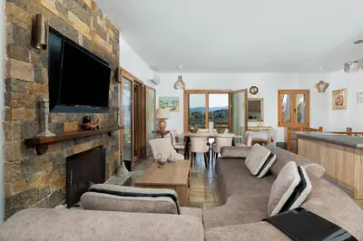 a living room with a stone fireplace and a tv at Villa Beis in Porto Rafti