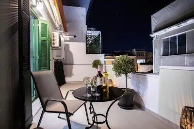 a small table and chairs on a balcony at night at Pandrosos Divine Suites in Athens