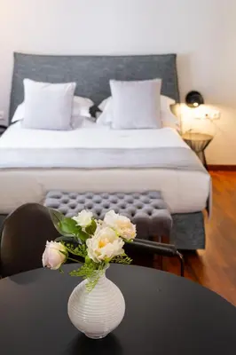 a vase with flowers on a table in a bedroom at Asty Luxury Apartments in Athens