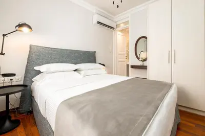 a white bedroom with a large bed and a table at Asty Luxury Apartments in Athens