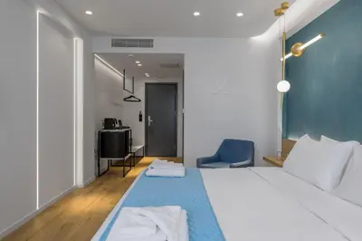 a bedroom with a large white bed with a blue rug at Acropolis Magenta Luxury Suites in Athens