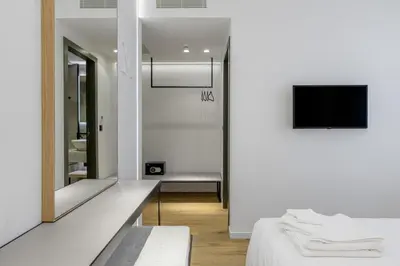 a white room with a bed and a mirror at Acropolis Magenta Luxury Suites in Athens