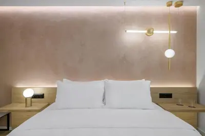 a bedroom with a white bed with two lamps at Acropolis Magenta Luxury Suites in Athens