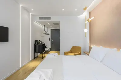 a bedroom with a large white bed and a chair at Acropolis Magenta Luxury Suites in Athens