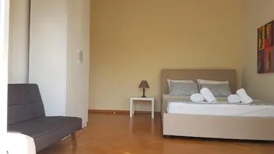 a bedroom with a bed with a chair and a couch at Orange Apartment - Athens Center, 3 BD, 1.5 BATH in Athens