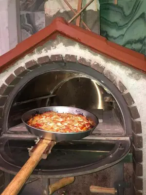 a pizza is being cooked in an oven at Ferienhaus Athens Marmor Garden in Kalívia Thorikoú