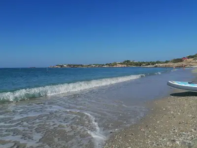a beach with a surfboard on the shore at Ferienhaus Athens Marmor Garden in Kalívia Thorikoú